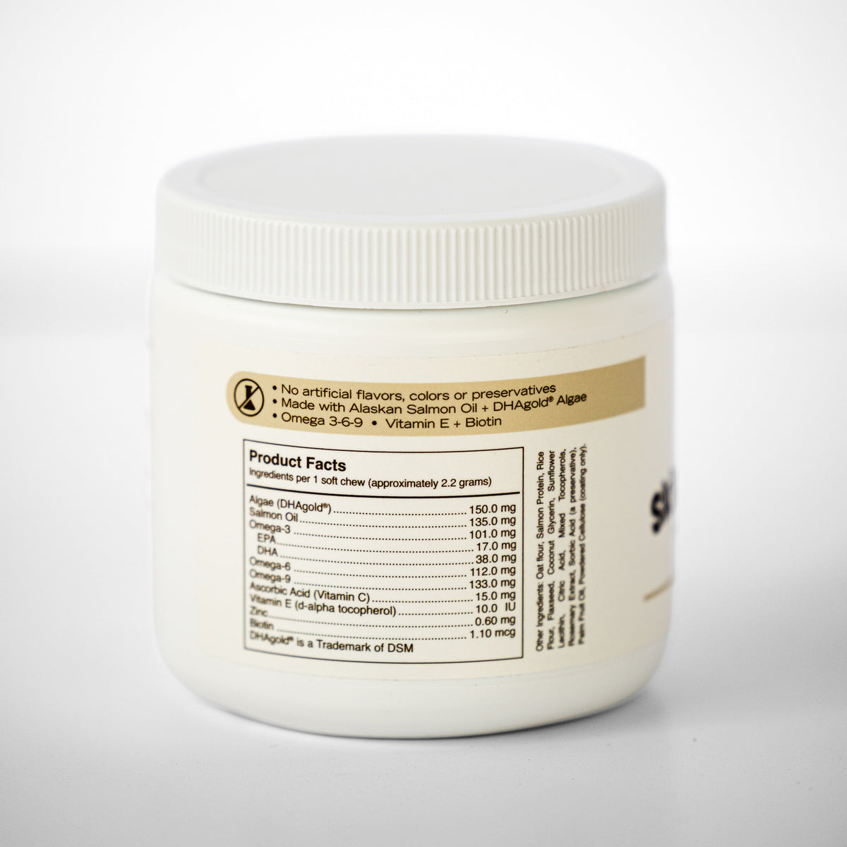A white plastic tub of salmon oil chews with a ribbed screw-on lid, showing the back label with product details, set against a clean white background.