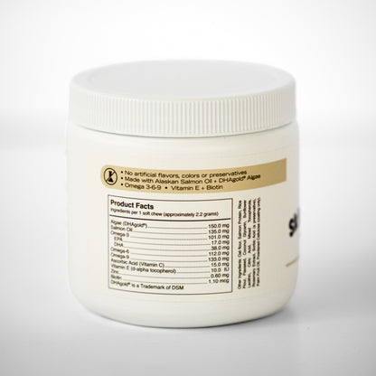 A white plastic tub of salmon oil chews with a ribbed screw-on lid, showing the back label with product details, set against a clean white background.
